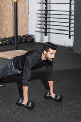 Fototapeta na wymiar Muslim man working out with dumbbells in gym.