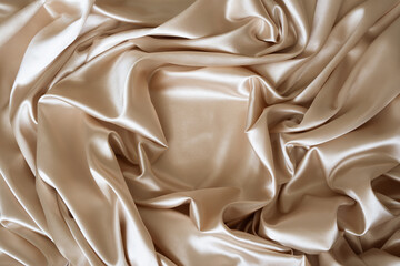 Beautiful elegant wavy beige or light brown satin silk fabric, abstract background design. Copy space. Card or banner