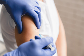 Cropped closeup image of doctor nurse in protective gloves taking shot with syringe making...