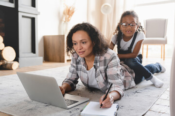 Busy african-american mother freelancer working on distance remotely on laptop, trying to...