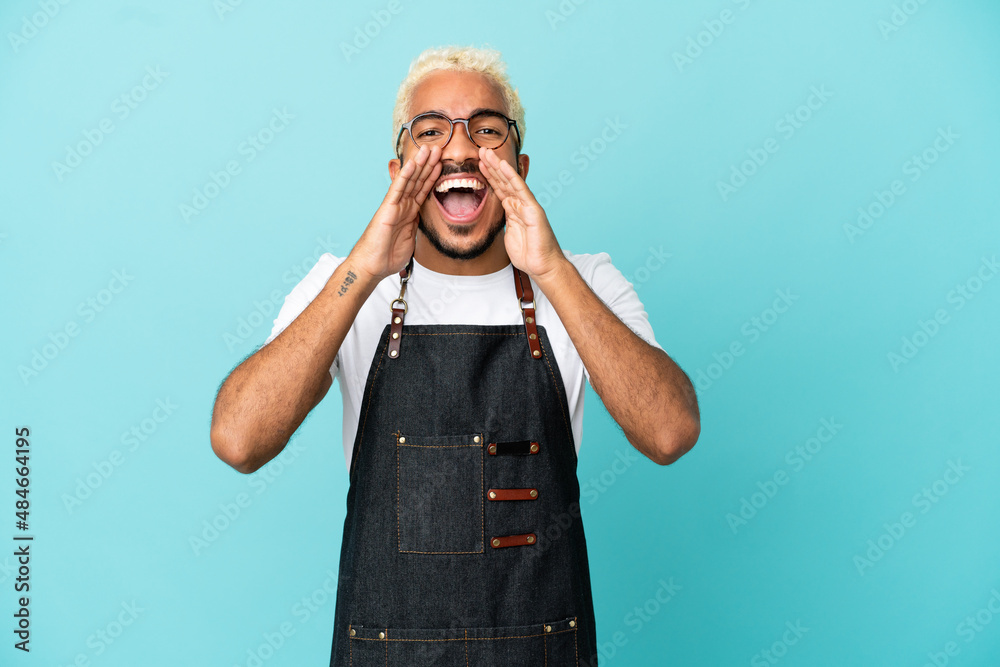 Wall mural restaurant colombian waiter man isolated on blue background shouting and announcing something