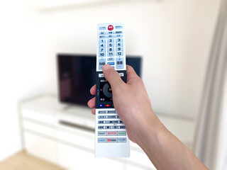 薄型テレビの前でリモコンをかざす手