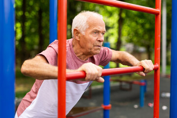 Obraz premium Sportive elderly man training on outdoor sports ground