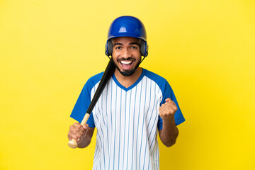 Young Colombian latin man playing baseball isolated on yellow background celebrating a victory in winner position