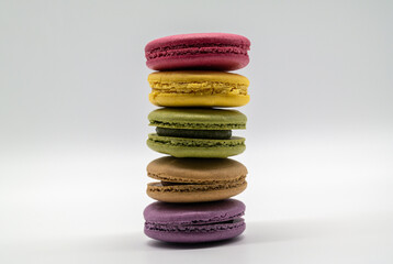 On top of the white background, sweet macaroons of various colors are piled up.