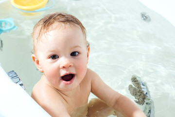 Fototapeta na wymiar Kid taking bath. Child bathing in bathtub. Little baby playing with water.