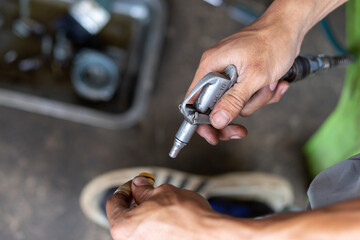 selective focus  air blow gun in the hands of a motorcyclist Cleaning motorbike parts with air