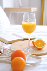 Oranges and orange juice in a glass on a white bed. Fresh oranges. Fruits lie on a white bed. Fruits close-up. Breakfast in bed. 