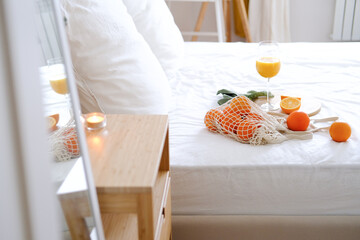 Oranges and orange juice in a glass on a white bed. Fresh oranges. Fruits lie on a white bed. Fruits close-up. Breakfast in bed. 