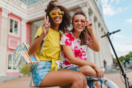 happy young girls friends smiling sitting in street