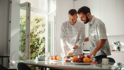 Stylish Young Adult Gay Couple at Home in Casual Clothes in Kitchen Area. Handsome Male Cutting Apples and Preparing Lunch. Partners Talking and have Fun. Cute LGBTQ Relationship Content.