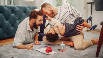 Loving LGBTQ Family Playing with Toys with Adorable Baby Boy at Home on Living Room Floor. Cheerful...