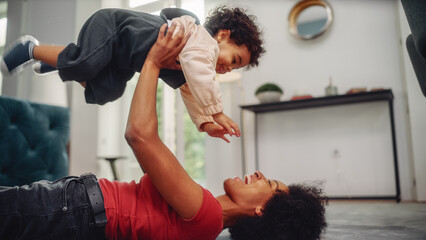 Beautiful African American Mother Playing with Adorable Baby Boy at Home on Living Room Floor....