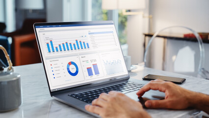 Close Up Of a Person's Hands Using Laptop Computer, Doing Data Analysis with Charts and Graphs. Young Man is Working from Modern Home, Using Touch Pad, Scrolling Content.