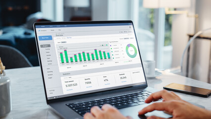 Close Up Of a Person's Hands Using Laptop Computer, Doing Data Analysis with Charts and Graphs. Young Man is Working from Modern Home, Using Touch Pad, Scrolling Content.
