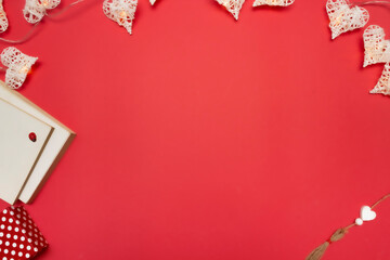 Gift box with polka dots, white books and beam of heart-shaped lights on a red background. Love valentine concept. Flat lay