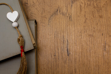 Wooden heart on grey books on wooden background. Love valentine concept. Flat lay