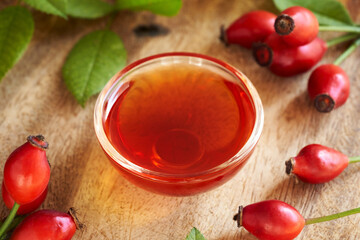 A bowl of rosehip seed oil with fresh rose hips