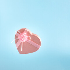 Pink heart-shaped gift on a pastel blue background. Idea for wedding or birthday. Minimal festival concept.