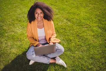 Above high angle view portrait of attractive cheerful girl sitting on grass using laptop learning remotely outdoors