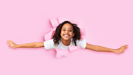 Happy excited cute african american little girl look through hole on pink paper, panorama