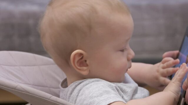 Father giving digital tablet computer to the kid to calm him down, happy child holding mobile device. 9-month-old baby boy face close-up. High quality 4k footage