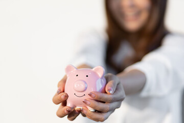 Close-up woman holding piggy bank smiling.