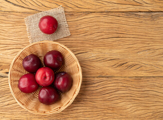 Plums in a basket over wooden table with copy space