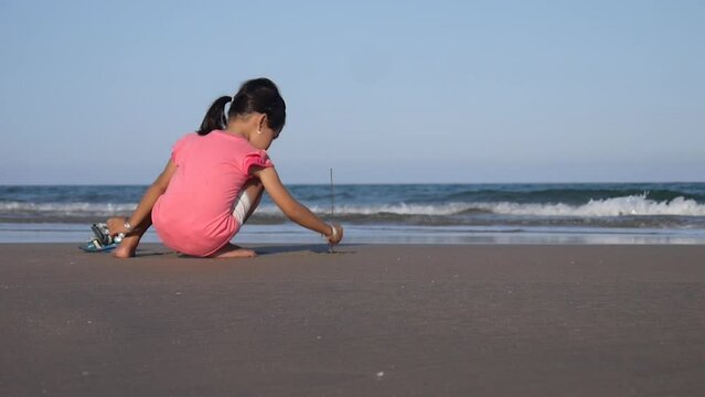 Little girl draws in the sand on the beach, Vietnam