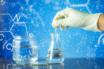 science glass tube experiment on blue background,Hands of clinician holding tools during scientific experiment ,Researcher is dropping the reagent into test tube, with chemical equations background,