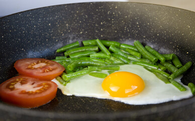 Fried eggs, tomatoes and beans in a frying pan. Healthy breakfast, natural food. The concept of a healthy lifestyle.