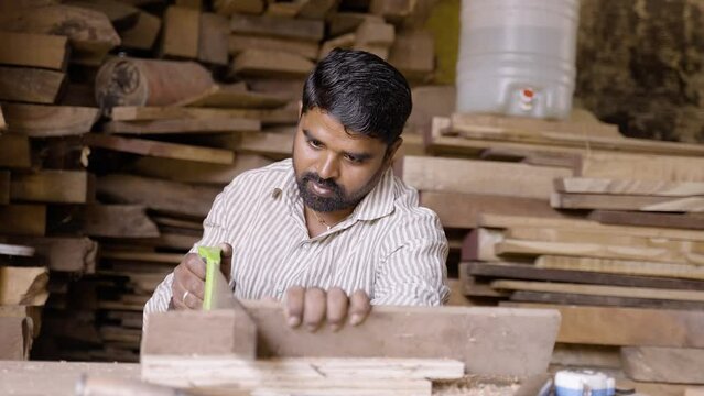 Indian carpenter manually cutting wood using sawing equipment - concept of Hard working, woodworker and craftsman and skilled labour.
