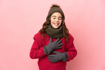 Little girl with winter hat isolated on pink background smiling a lot