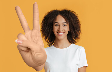 Cheerful mixed race young lady showing peace gesture