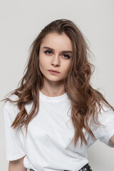 Fototapeta premium Pretty serious woman with cute face and hairstyle in white t-shirt look at the camera in studio. Fashion girl