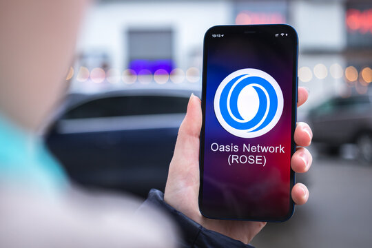 Oasis Network ROSE coin symbol. Trade with cryptocurrency, digital and virtual money, mobile banking. Hand with smartphone, screen with crypto icon close-up photo