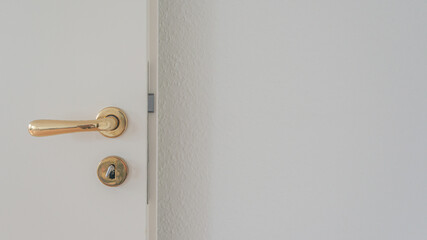 White door with golden doorhandle and key in the locker with blur copy space wall background.