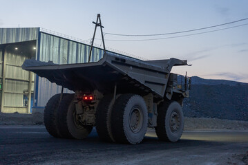 A dump truck drives through a gold mining site in the evening