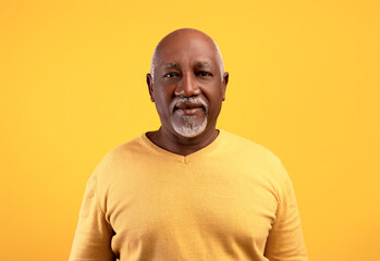 Portrait of happy elderly black man looking at camera over orange studio background