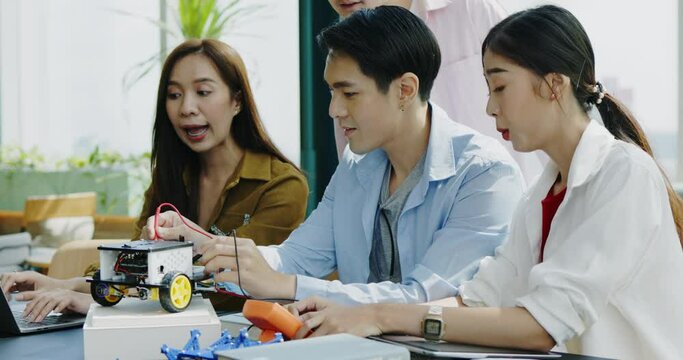 Group Asian businessmen sit meeting to test invention of car model in coworking space. Startup brainstorm technical idea with determination in conference room. Cooperation with professional teamwork