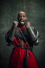 Half-length portrait of dark skinned man, medieval warrior or knight wearing armour shouting as...