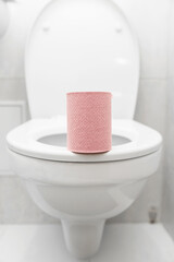 a roll of pink toilet paper is on the toilet in the bathroom.