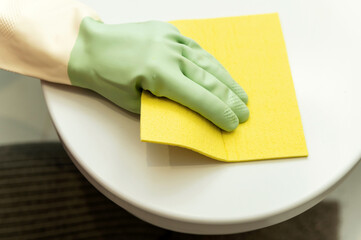 close-up of a hand cleaning a toilet lid with a yellow rag