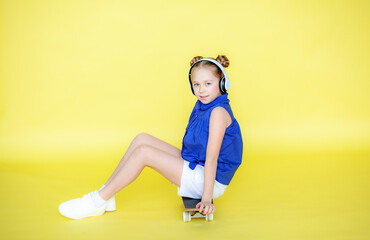 A funny little blonde girl of 10 years old in everyday bright clothes poses in isolation against...