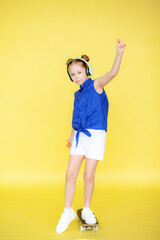 Fototapeta na wymiar A funny little blonde girl of 10 years old in everyday bright clothes poses in isolation against the yellow background of the studio. The concept of a child's lifestyle. Layout of the copy space. Hold