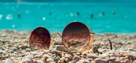 Retro sunglasses lie on the beach