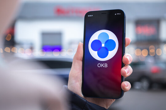 OKB coin symbol. Trade with cryptocurrency, digital and virtual money, mobile banking. Hand with smartphone, screen with crypto icon close-up photo