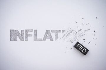 Word hand writing INFLATION is deleted by black FED eraser on white paper background copy space....