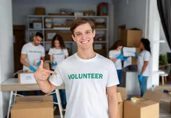 I'm a volunteer. Cheerful activist guy pointing finger at himself and volunteer inscription on his t-shirt