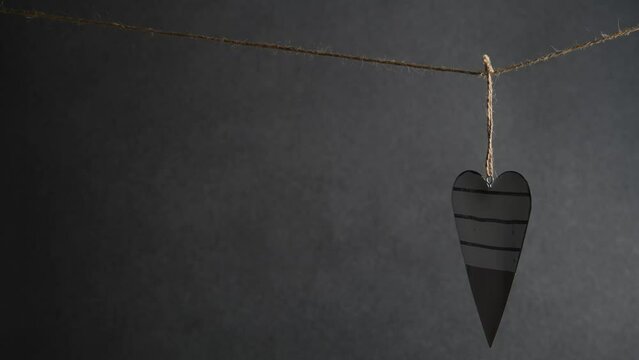 a black and white heart hangs on a rope on a gray background. Valentine's Day, Love. with copy space